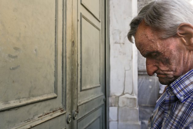 A pensioner waits outside a branch of the National Bank to receive part of his pension in Athens