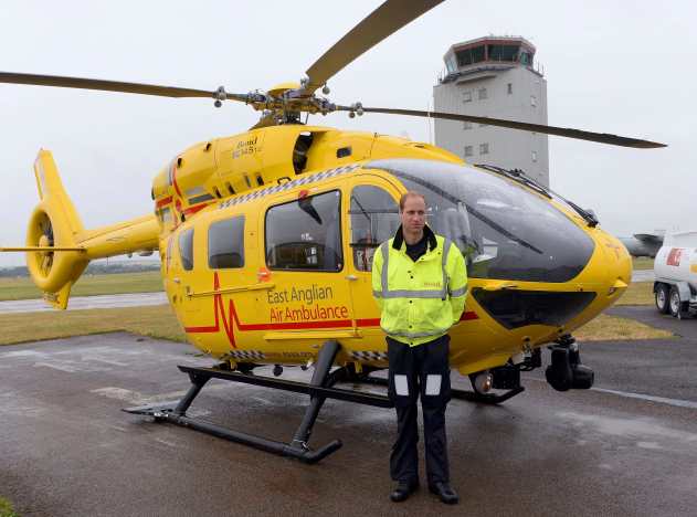 Britain's Prince William poses by his helicopter as he begins his new job as a co-pilot with the East Anglian Air Ambulance at Cambridge Airport