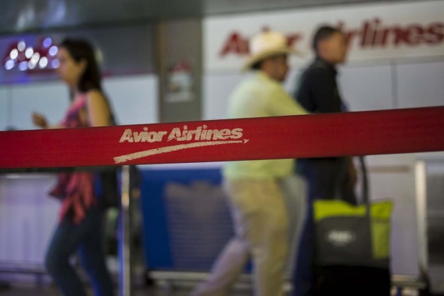 People walk past the counter of Avior Airlines at the Simon Bolivar airport in Caracas July 17, 2015. Venezuelan airline Avior is purchasing 12 used planes to offer new international routes from the South American nation, where foreign carriers have slashed flights due to currency controls. Avior President Jorge Anez said in an interview on Thursday that the company was purchasing six planes from Europe's Airbus Group and six from Chicago-based Boeing CO for a total of about $150 million. REUTERS/Marco Bello