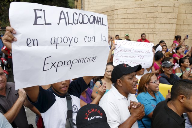 Venezuelan government supporters hold placards and shout outside a facility used by Empresas Polar as a distribution center, during the occupation of its installations by government representatives in Caracas July 30, 2015. The placard reads: "El Algodonal, in support of the expropriation". REUTERS/Carlos Garcia Rawlins