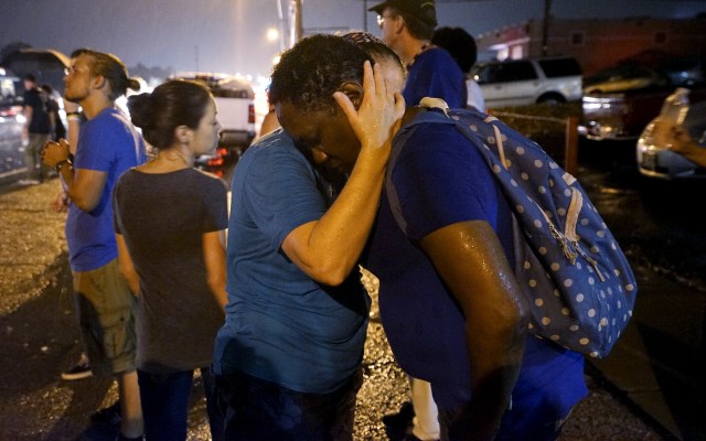Un tiroteo se produjo la noche del domingo en Ferguson, Misuri, después de que un día de manifestaciones pacíficas por el aniversario de la muerte de un adolescente negro desarmado por un policía blanco diese paso a un enfrentamiento entre la policía y los manifestantes, dijo un testigo de Reuters. En la imagen, una mujer blanca abraza a una negra mientras rezan bajo la lluvia en el lugar donde un año antes se produjeron los disturbios por la muerte de Michael Brown, el 9 de agosto de 2015. REUTERS/Rick Wilking