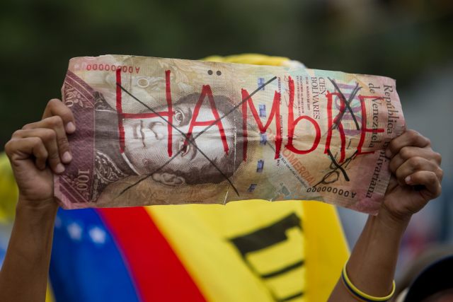 CAR01. CARACAS (VENEZUELA), 08/08/2015.- Una persona sostiene en su mano un billete de 100 bolívares fuertes falso, con la para "hambre" durante una manifestación hoy, sábado 8 de agosto de 2015, en la ciudad de Caracas (Venezuela). La alianza opositora venezolana Mesa de la Unidad Democrática (MUD) admitió que fue escasa la asistencia a la manifestación, pero subrayó que ello no pone en dudas el triunfo que prevé en los comicios de diciembre. La convocatoria a marchar por todas las capitales de los 24 estados del país, y por zonas del centro-este de Caracas, "contra el hambre, contra el hampa por la libertad, por la unidad", finalmente reunió a unas pocas decenas de personas en una sola calle de la capital venezolana. EFE/MIGUEL GUTIERREZ