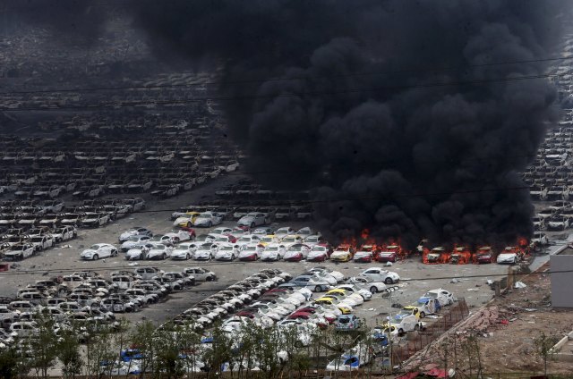 Smoke rises as damaged vehicles are seen burning near the site of Wednesday night's explosions, at Binhai new district in Tianjin, China, August 15, 2015. Chinese police have for the first time confirmed deadly sodium cyanide at the site of two huge warehouse blasts that killed 85 people, state media said on Saturday, as a series of new, small explosions were heard and small fires broke out. REUTERS/Stringer CHINA OUT. NO COMMERCIAL OR EDITORIAL SALES IN CHINA      TPX IMAGES OF THE DAY