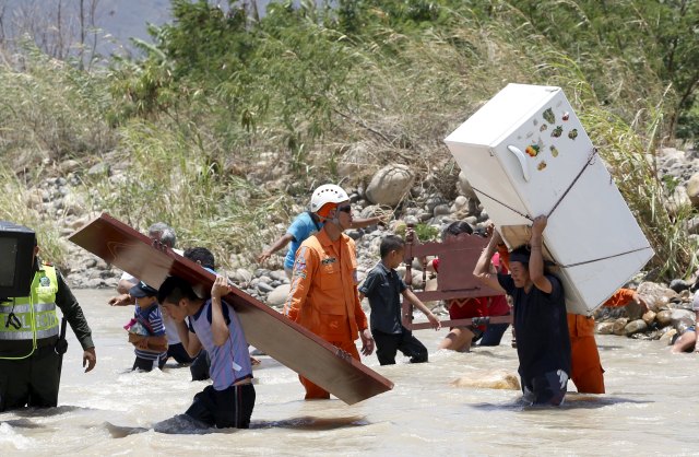 People carry their belongings while crossing the Tachira river border with Venezuela into Colombia, near Villa del Rosario village August 25, 2015. The ongoing crisis on the border between Colombia and Venezuela should not be used for political point-scoring by leaders in either country ahead of elections in coming months, the Colombian government said on Tuesday. REUTERS/Jose Miguel Gomez