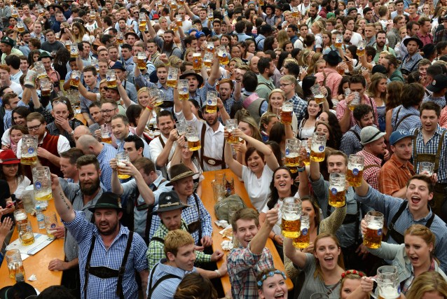 Visitors to the Oktoberfest beer festival raise their beers after the festival's opening in Munich, southern Germany, on September 19, 2015. The world biggest Beer festival Oktoberfest will start on September 19, 2015 and take place until October 4, 2015.  AFP PHOTO / CHRISTOF STACHE