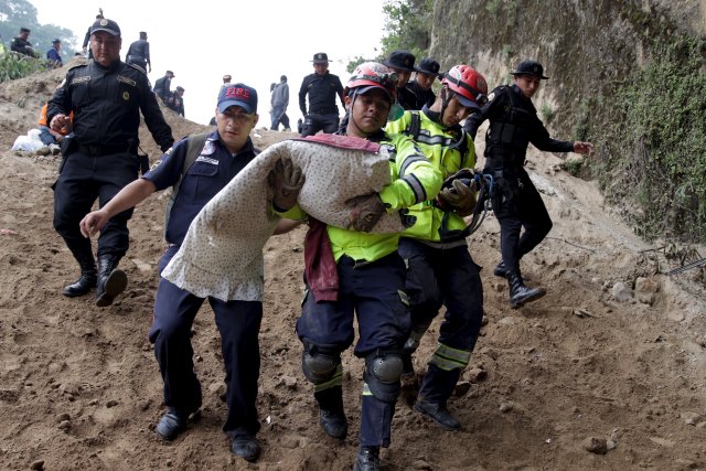 Firefighter carries the body of a child retrieved from a mudslide in Santa Catarina Pinula, on the outskirts of Guatemala City