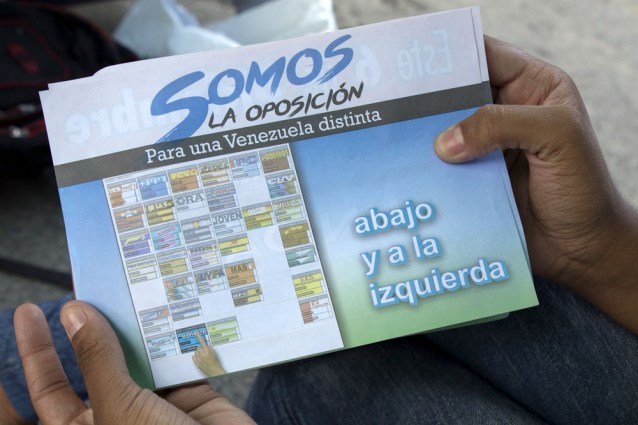 A flyer with information on how to vote for MIN Unidad Party is displayed by a woman in Caracas