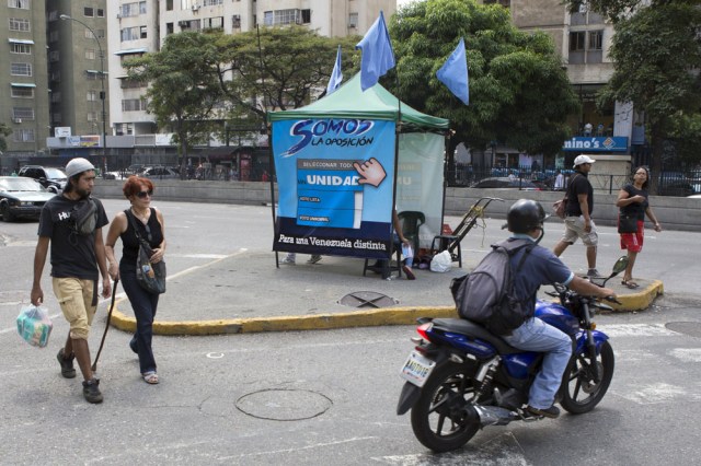 People pass by a tent for MIN Unidad Party in a main avenue in Caracas