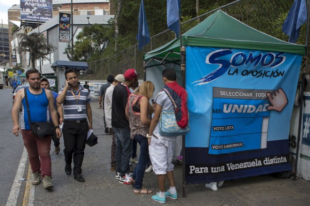 People pass by a tent for MIN Unidad Party in a main avenue in Caracas