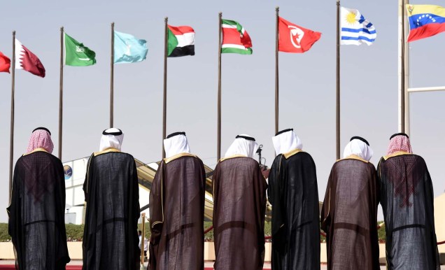 Saudi officials stand in front of the flags of countries being hosted by Saudi Arabia to attend the 4th summit of Arab States and South American countries, during the welcoming ceremony held at King Khalid International airport in Riyadh, on November 10, 2015. Arab leaders and top officials from South America are converging on Saudi Arabia for a summit aiming to strengthen ties between the geographically distant but economically powerful regions. AFP PHOTO / FAYEZ NURELDINE