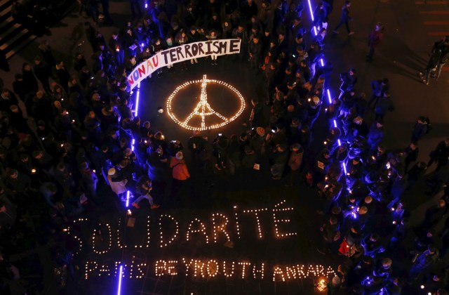 People gather around candles during a ceremony for the victims the day after a series of deadly attacks in the French capital of Paris, in Lausanne, Switzerland November 14, 2015. The banner reads : "No to terrorism" and the candles reads : Solidarity Paris Beyrouth Ankara" REUTERS/Denis Balibouse TPX IMAGES OF THE DAY