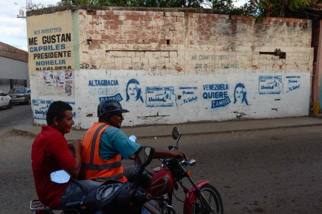 A motorcyclist passes   by a graffiti depicting a Venezuelan opposition candidate for the upcoming legislative elections Rumualda Olivo in the Altagracia de Orituco town in Guarico state, Venezuela, on November 26, 2015. An opposition candidate in Venezuela's upcoming legislative elections was shot dead during an event Wednesday. "Luis Manuel Diaz, local leader of the Democratic Action party in Altagracia de Orituco (Guarico state) has just been shot dead," the party's chairman Henry Ramos Allup said on Twitter. AFP PHOTO/ FEDERICO PARRA / AFP / FEDERICO PARRA