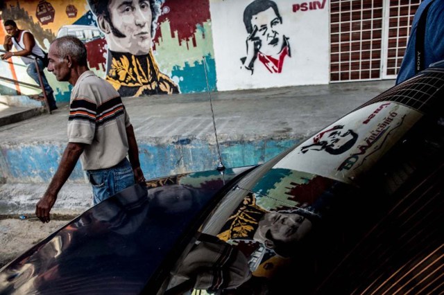 A man walks next to a propaganda graffiti showing South American independence hero Simon Bolivar (L) and late Venezuelan President (1999-2013) Hugo Chavez in Petare shantytown, Caracas on November 4 , 2015. About 35% to 40% of Venezuelans are "independent" but not necessarily apathetic, according to the polling firm Datanalisis.    AFP PHOTO/FEDERICO PARRA / AFP / FEDERICO PARRA