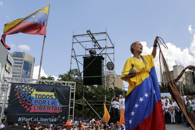 Lilian Tintori, wife of jailed Venezuelan opposition leader Leopoldo Lopez reacts as she wears a dress with the Venezuelan flag colors given by a supporter during a campaign rally of deputies candidates for the National Assembly for the Venezuelan coalition of opposition parties Democratic Unity Roundtable (MUD), in Caracas, November 29, 2015. Venezuela will hold parliamentary elections on December 6. REUTERS/Marco Bello. FOR EDITORIAL USE ONLY. NO RESALES. NO ARCHIVE.