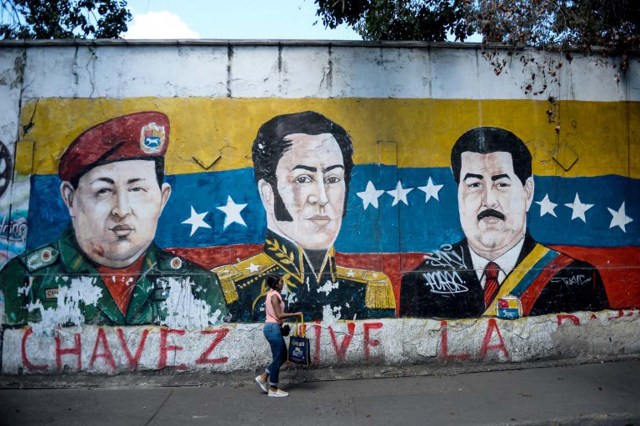 Un graffiti de propaganda electoral que retrata al fallecido presidente venezolano (1999-2013) Hugo Chavez (L), al héroe de la independencia sudamericano Simón Bolívar (C) y al presidente venezolano Nicolás Maduro en un muro de la barriada Petare en Caracas el 1 de diciembre de 2015. Dieciséis años En la última "revolución" izquierdista del presidente Hugo Chávez, las encuestas de opinión indican que la oposición está lista para ganar las elecciones legislativas del domingo por primera vez desde que el líder llegó al poder. AFP PHOTO / FEDERICO PARRA / AFP / FEDERICO PARRA