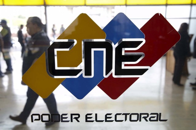 People walk past a logo of the National Electoral Council (CNE) at its headquarters in Caracas December 2, 2015. Venezuela will hold parliamentary elections on December 6. REUTERS/Carlos Garcia Rawlins