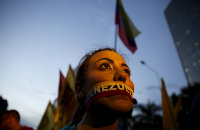 An opposition supporter tapes her mouth with the colours of Venezuela flag during a campaign rally with candidates for the National Assembly from the Venezuelan coalition of opposition parties (MUD) in Caracas December 3, 2015. Polarized Venezuela heads to the polls this weekend with a punishing recession forecast to rock the ruling Socialists and propel an optimistic opposition to its first legislative majority in 16 years. REUTERS/Nacho Doce