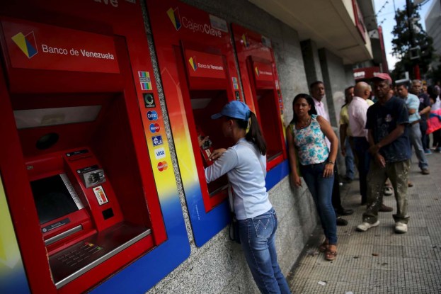 Venezuelans line up to withdraw cash from an automated teller machine (ATM) outside a Venezuela branch in Caracas December 4, 2015. Polarized Venezuela heads to the polls this weekend with a punishing recession forecast to rock the ruling Socialists and propel an optimistic opposition to its first legislative majority in 16 years. REUTERS/Nacho Doce