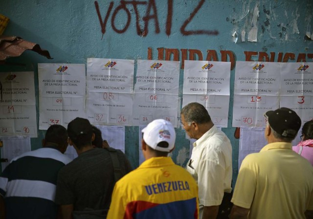 Citizens look for their names in the electoral roster at a polling station in the low income Petare neighborhood in Caracas, December 6, 2015, during the Venezuela's legislative election. For the first time in 16 years of "Bolivarian revolution" under late president Hugo Chavez and his successor Nicolas Maduro, polls show their rivals could now win a majority in the National Assembly. AFP PHOTO/ LUIS ROBAYO / AFP / LUIS ROBAYO