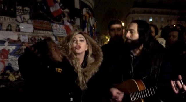 A still image from a video shows singer Madonna (C) giving an impromptu street concert at the Place de la Republique in Paris December 10, 2015, the site of massed tributes for the victims of the recent Paris attacks. Madonna performed John Lennon's 'Imagine' and her song 'Ghosttown', accompanied just by a guitar in the middle of the cold night.  REUTERS TV      TPX IMAGES OF THE DAY