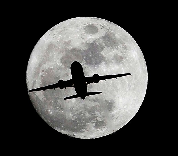 La silueta de un avión se recorta ante la luna casi llena en su ruta hacia el aeropuerto internacional de Los Ángeles, cerca de Whittier, California, el jueves 24 de diciembre de 2015. (AP Foto/Nick Ut)