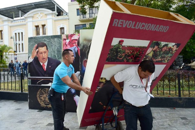 Venezuelan National Assembly employees remove from the building  pictures of late President Hugo Chavez, in Caracas on January 6, 2016. Venezuela's opposition on Tuesday broke the government's 17-year grip on the legislature and vowed to force out President Nicolas Maduro despite failing for the time being to clinch its hoped-for "supermajority." AFP PHOTO/RONALDO SCHEMIDT / AFP / RONALDO SCHEMIDT