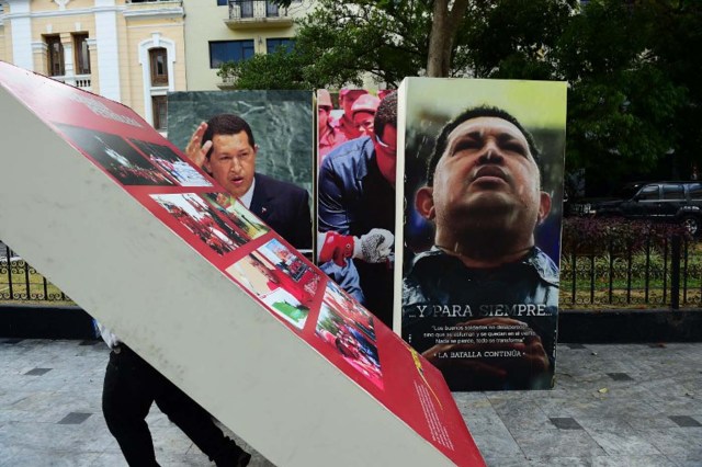 National Assembly employees remove from the building  pictures of late President Hugo Chavez, in Caracas on January 6, 2016. Venezuela's opposition on Tuesday broke the government's 17-year grip on the legislature and vowed to force out President Nicolas Maduro despite failing for the time being to clinch its hoped-for "supermajority." AFP PHOTO/RONALDO SCHEMIDT / AFP / RONALDO SCHEMIDT