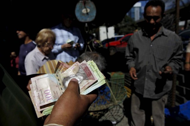 A man counts bolivar notes, at a vegetable street market in Caracas January 16, 2016. Venezuela's socialist government decreed an "economic emergency" on Friday that will expand its powers and published the first data in a year that shows the depth of a recession fueled by low oil prices and a sputtering state-led model. The central bank, which has been lambasted by critics of President Nicolas Maduro's government for hiding statistics since the end of 2014, said the South American OPEC nation's economy shrank 4.5 percent in the first nine months last year. Inflation soared in that period to an annual rate of 141.5 percent, the world's worst. REUTERS/Carlos Garcia Rawlins