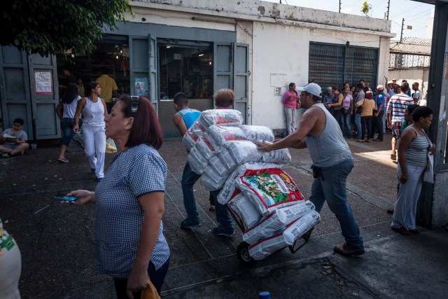 CAR01. CARACAS (VENEZUELA), 16/01/2016.- Un par de hombres ingresan alimento para perros en un abasto hoy, sábado 16 de enero de 2016, en la ciudad de Caracas (Venezuela). Venezuela, con las mayores reservas probadas de petróleo del mundo, se declaró en emergencia económica para atender la situación del país que después de un año de opacidad reveló una inflación interanual de 141,5 por ciento -la más alta de toda su historia-, y una contracción del 4,5 por ciento. EFE/MIGUEL GUTIÉRREZ