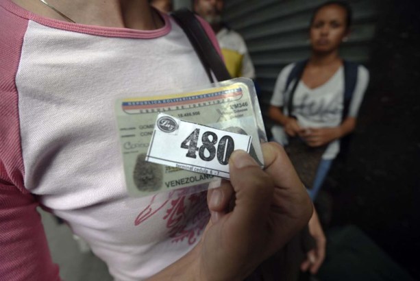 A woman holding a number to buy food waits outside a supermarket in Caracas, Venezuela on January 21, 2016. Trade unions demonstrated Wednesday outside the Venezuelan National Assembly against the economic emergency decrees issued by President Nicolas Maduro, who was meeting with the legislative commission studying whether parliament will approve the executive measures.  AFP PHOTO/JUAN BARRETO / AFP / JUAN BARRETO