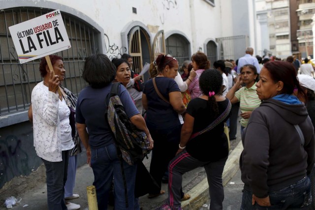 A elder woman holds a placard that reads, "The last user of the line", while she waits next to others in a line for the elderly outside a PDVAL, a state-run supermarket, to buy chicken in Caracas January 22, 2016.  Venezuela's opposition refused on Friday to approve President Nicolas Maduro's "economic emergency" decree in Congress, saying it offered no solutions for the OPEC nation's increasingly disastrous recession. Underlining the grave situation in Venezuela, where a plunge in oil prices has compounded dysfunctional policies, the International Monetary Fund on Friday forecast an 8 percent drop in gross domestic product and 720 percent inflation this year. REUTERS/Carlos Garcia Rawlins