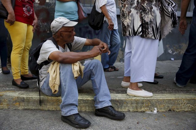 Aman sits on the sidewalk, while he waits next to others in a line for the elderly outside a PDVAL, a state-run supermarket, to buy chicken in Caracas January 22, 2016.  Venezuela's opposition refused on Friday to approve President Nicolas Maduro's "economic emergency" decree in Congress, saying it offered no solutions for the OPEC nation's increasingly disastrous recession. Underlining the grave situation in Venezuela, where a plunge in oil prices has compounded dysfunctional policies, the International Monetary Fund on Friday forecast an 8 percent drop in gross domestic product and 720 percent inflation this year. REUTERS/Carlos Garcia Rawlins