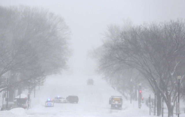 Capitol Hill police and snow plows work in Constitution Avenue during a winter storm in Washington January 23, 2016. A winter storm dumped nearly 2 feet (58 cm) of snow on the suburbs of Washington, D.C., on Saturday before moving on to Philadelphia and New York, paralyzing road, rail and airline travel along the U.S. East Coast.      REUTERS/Joshua Roberts