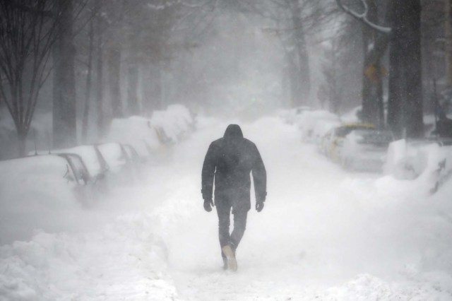A man walks along a street covered by snow during a winter storm in Washington January 23, 2016. A winter storm dumped nearly 2 feet (58 cm) of snow on the suburbs of Washington, D.C., on Saturday before moving on to Philadelphia and New York, paralyzing road, rail and airline travel along the U.S. East Coast. REUTERS/Carlos Barria      TPX IMAGES OF THE DAY