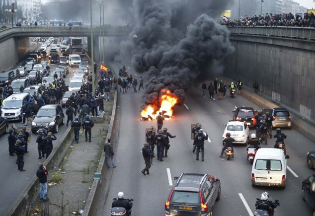 Anti-riot policemen arrive as taxi drivers block the traffic with a fire during a demonstration against the VTC (transport vehicle with chauffeur) on January 26, 2016 on the ringroad (peripherique)  at porte Maillot in Paris. AFP PHOTO / THOMAS SAMSON / AFP / THOMAS SAMSON