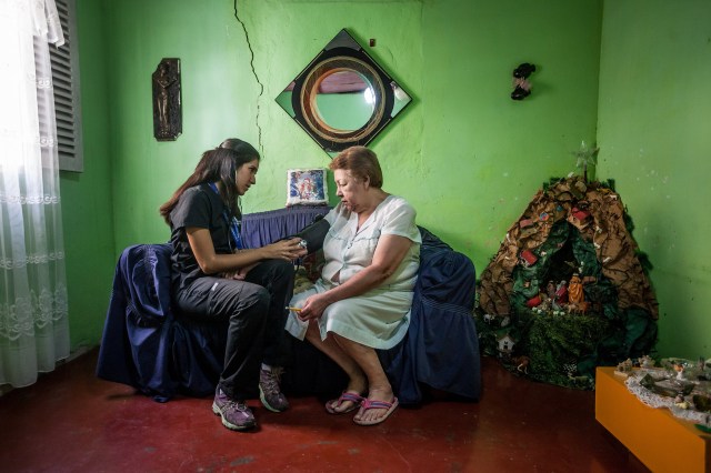 Daniella Liendo, estudiante de medicina de la UCV, toma la presión arterial a una residente del barrio marginal 23 de Enero, en el oeste de Caracas. PHOTO: MIGUEL GUTIÉRREZ PARA THE WALL STREET JOURNAL.
