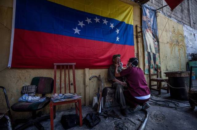 William Saavedra, un estudiante de ortodoncia, ofrece una consulta gratuita a un residente de bajos recursos del barrio 23 de Enero, en Caracas. PHOTO: MIGUEL GUTIÉRREZ PARA THE WALL STREET JOURNAL