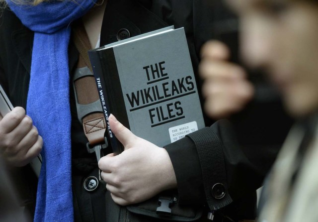 A supporter of WikiLeaks founder julian Assange holds a copy of The WikiLeaks Files outside the Ecuadorian embassy in central London, Britain February 5, 2016. Assange should be allowed to go free from the Ecuadorian embassy in London and be awarded compensation for what amounts to a three-and-a-half-year arbitrary detention, a U.N. panel ruled on Friday. REUTERS/Toby Melville