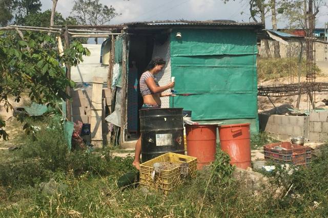Una mujer se baña con agua guardada en contenedores fuera de su casa en San Josecito, lo cual puede servir de incubadora a los mosquitos que transmiten el zika. PHOTO: SARA SCHAEFER MUÑOZ/THE WALL STREET JOURNAL