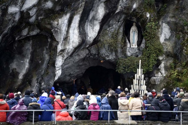 Pilgrim gather under the statue of the Virgin Mary inside the Massabielle grotto on February 11, 2016 for the 158th anniversary of the virgin Mary's apparition to Bernadette Soubirous in Lourdes, Southern France.  / AFP / PASCAL PAVANI