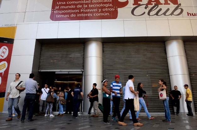 People remain outside a closed mall in Caracas on February 10, 2016. Venezuelans who flocked Wednesday to malls, found them closed and dark, since the government ordered an electricity rationing due to the drought taking place in the country. AFP PHOTO/FEDERICO PARRA / AFP / FEDERICO PARRA