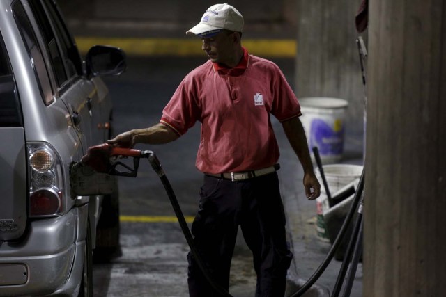 A worker pumps gas into a vehicle at a gas station which belongs to PDVSA in Caracas, February 17, 2016. REUTERS/Marco Bello