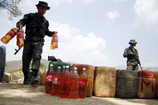 A Venezuelan soldier collects containers with gasoline abandoned by smugglers near the Colombian border in San Antonio, in the state of Tachira, February 17, 2016. REUTERS/Carlos Eduardo Ramirez. EDITORIAL USE ONLY. NO RESALES. NO ARCHIVE.