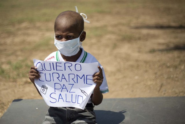 Oliver Sánchez, de 8 años, sostiene un cartel durante una protesta contra la escasez de medicamentos y suministros médicos en Caracas, el viernes 26 de febrero de 2016. (Foto AP/Ariana Cubillos)