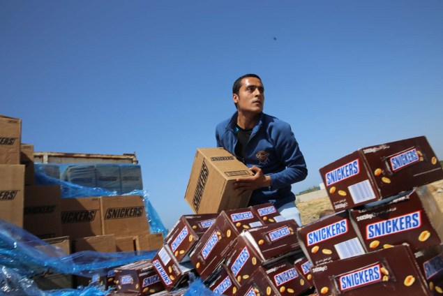Un trabajador palestino avienta cajas del chocolate Snickers a un hoyo para que sean incendiadas en las afueras de la ciudad de Gaza, el jueves 10 de marzo de 2016. (Foto AP/Adel Hana)