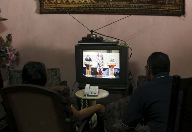 A couple watches on television as U.S. President Barack Obama (L) and his Cuban counterpart Raul Castro hold a joint news conference in Havana, March 21, 2016. REUTERS/Stringer EDITORIAL USE ONLY. NO RESALES. NO ARCHIVE      TPX IMAGES OF THE DAY