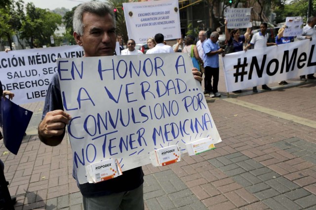 A man holds a placard with medicine boxes attached to it that reads "In all honesty ... I convulsed by not having medicine" during a protest due to the lack of medicines in Caracas, April 13, 2016. REUTERS/Marco Bello