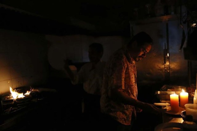 Unos trabajadores de un restaurante intentan completar unas ordenes durante un apagon en Caracas, jun 27, 2014. Venezuela adelantará su huso horario en 30 minutos a partir del 1 de mayo, como una medida para ahorrar electricidad, revirtiendo una de las medidas bandera del gobierno socialista del fallecido Hugo Chávez. REUTERS/Carlos Garcia Rawlins