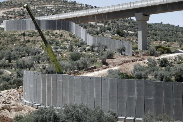 Israeli workers place a new section of Israel's separation concrete barrier in the Cremisan Valley, adjacent to the Christian Palestinian town of Beit Jala, in the Israeli-occupied West Bank, on April 21, 2016. Original The route of the barrier was slated to separate the Cremisan monastery from the NEIGHBOURING convent and vineyards but following a Palestinian appeal Israel's High Court issued two separate rulings in 2015 ordering the government to Consider alternative routes while Allowing work to continue on the segment of the barrier not Directly impacting the monastery and the convent. THOMAS COEX / AFP