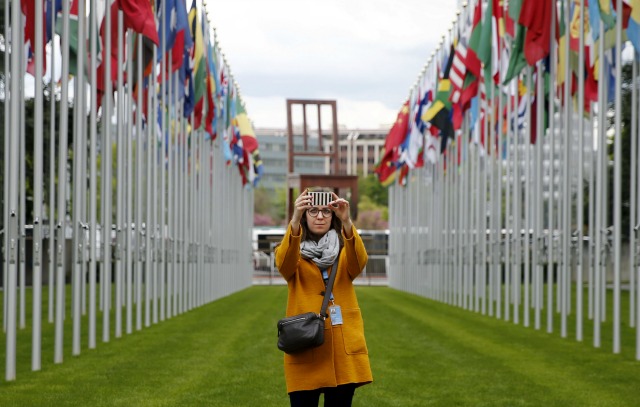 Un personal toma una autofoto en el callejón banderas en la sede europea de las Naciones Unidas en Ginebra, Suiza, 26 de abril de 2016. REUTERS / Denis Balibouse